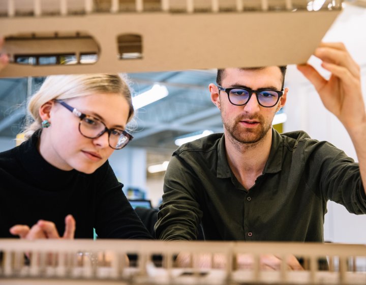 Interior design students looking inside a model.