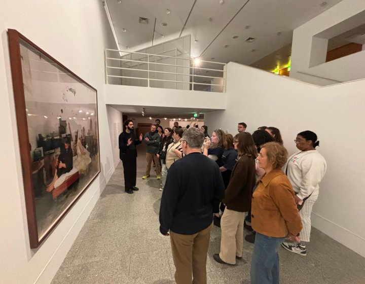 A group of students looking at a large photograph displayed in a gallery