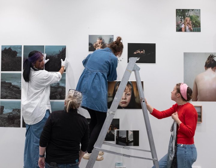 Four people hanging a photography exhibition