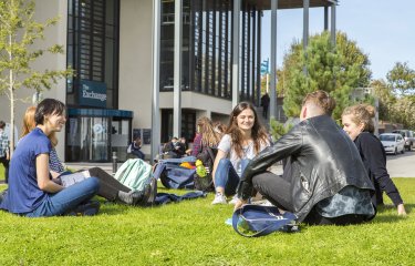 Students sitting on grass at Penryn campus.
