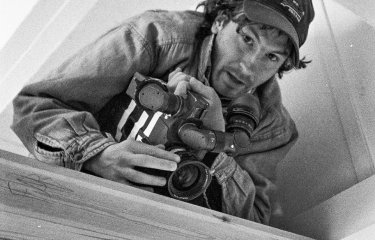 A man wearing a cap and holding a camera